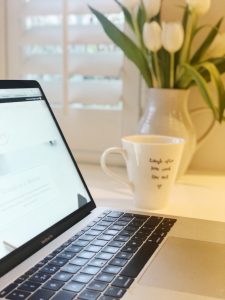 Image of lap top with coffee cup and flowers in the back ground the power of an hour may take place in the office.