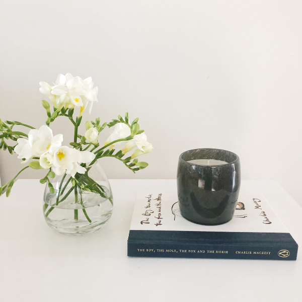 Calm lifestyle setup with flowers, book, and candle symbolising mindfulness and letting go of the ball