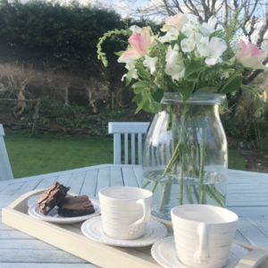two cups and a vase of flowers outside on a table, discussing kindness and being too kind
