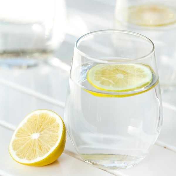 keep the body hydrated. image of a glass of water with lemon slice