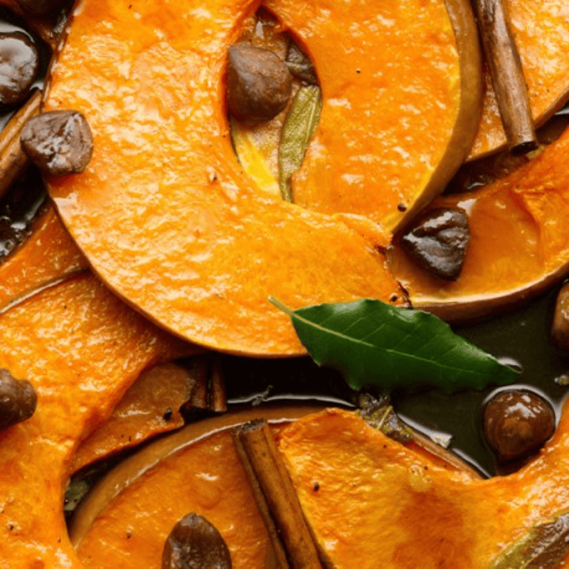 Pumpkin season recipes : close up of roasted pumpkin with bay leaves cinnamon and chestnuts
